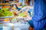 Bio-regionale Außer-Haus-Verpflegung, 2 Personen bedienen sich mit Gemüse am Buffet.